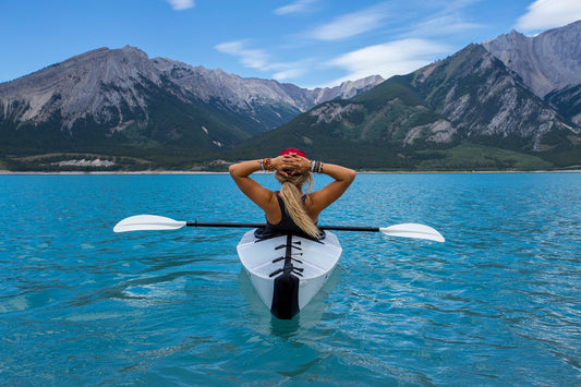 woman in kayak on a lake at the base of a mountain